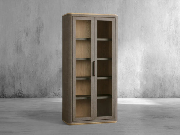 Tall wooden cabinet with glass doors against a gray concrete wall.
