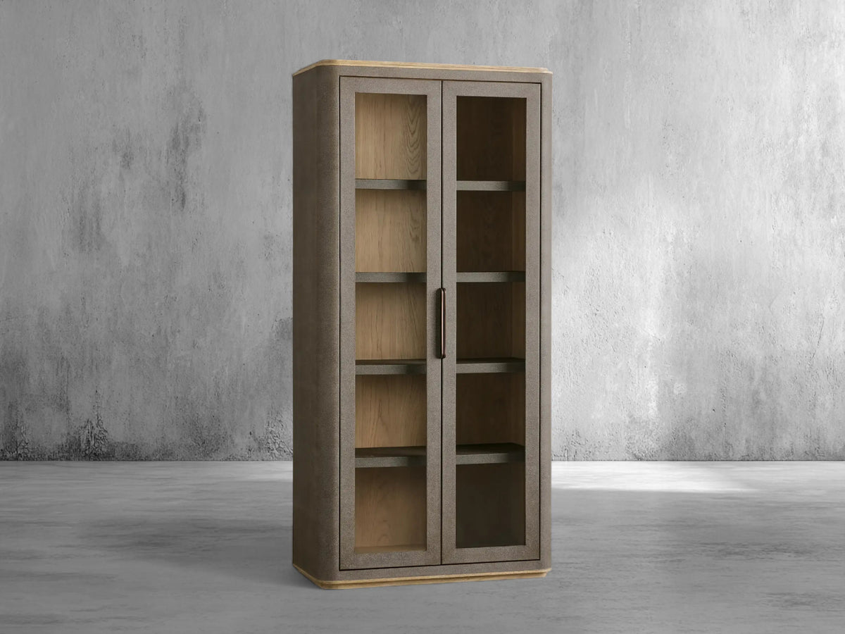 Tall wooden cabinet with glass doors against a gray concrete wall.